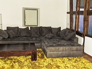 A sectional sofa with a matching ottoman and a coffee table in a room with a yellow shaggy rug. - Alte Scheune Loft by Interhome (Idstein)