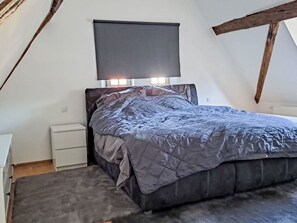 A bedroom with a bed, bedside tables, a window, and a ceiling with exposed beams. - Alte Scheune Loft by Interhome (Idstein)