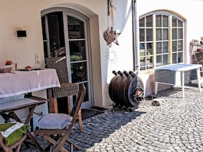 A cobblestone patio with outdoor seating, a barrel, and a table with a white tablecloth. - Alte Scheune Loft by Interhome (Idstein)