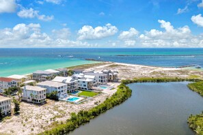 A coastal residential area with multiple two-story houses, a swimming pool, and a marina with boats. - 🌴Blue Skies & Tail Winds | Private Pool | 4 Bikes | Private Beach Access🌴 (Destin)