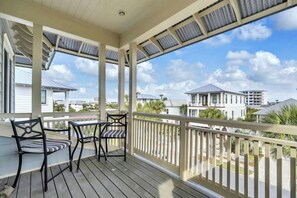 A covered outdoor area with a wooden deck, two chairs, and a table. - 🌴Blue Skies & Tail Winds | Private Pool | 4 Bikes | Private Beach Access🌴 (Destin)