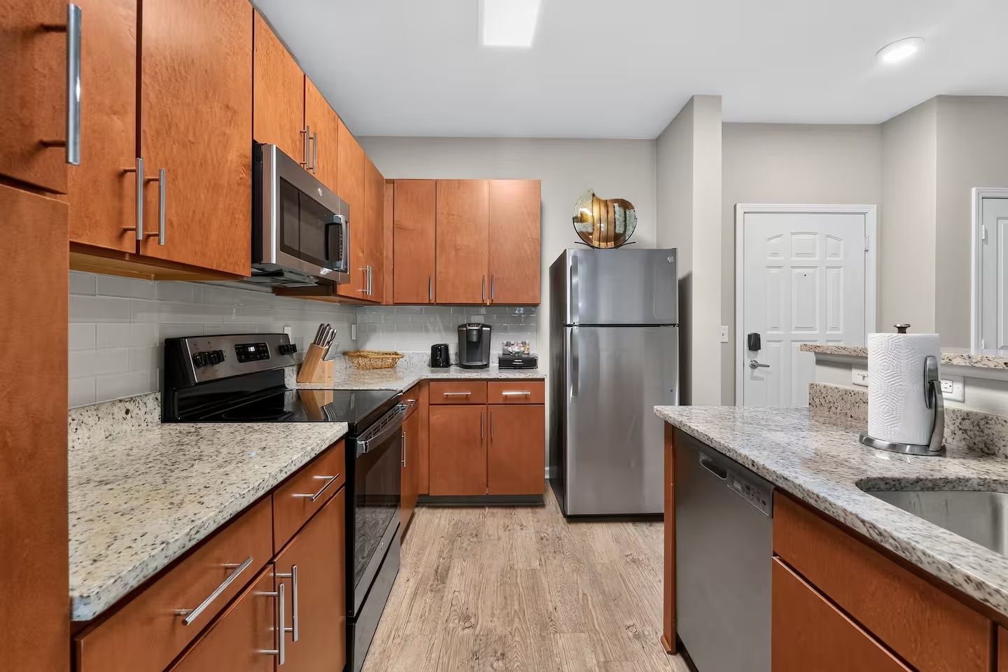 A modern kitchen with wooden cabinets, stainless steel appliances, and granite countertops.