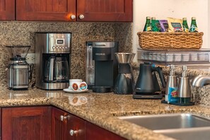 A kitchen with a coffee maker, a Keurig, a coffee pot, a blender, and a basket of bottled drinks. - 1st floor, no steps, king beds, beach, pool, golf (Waikoloa Village)