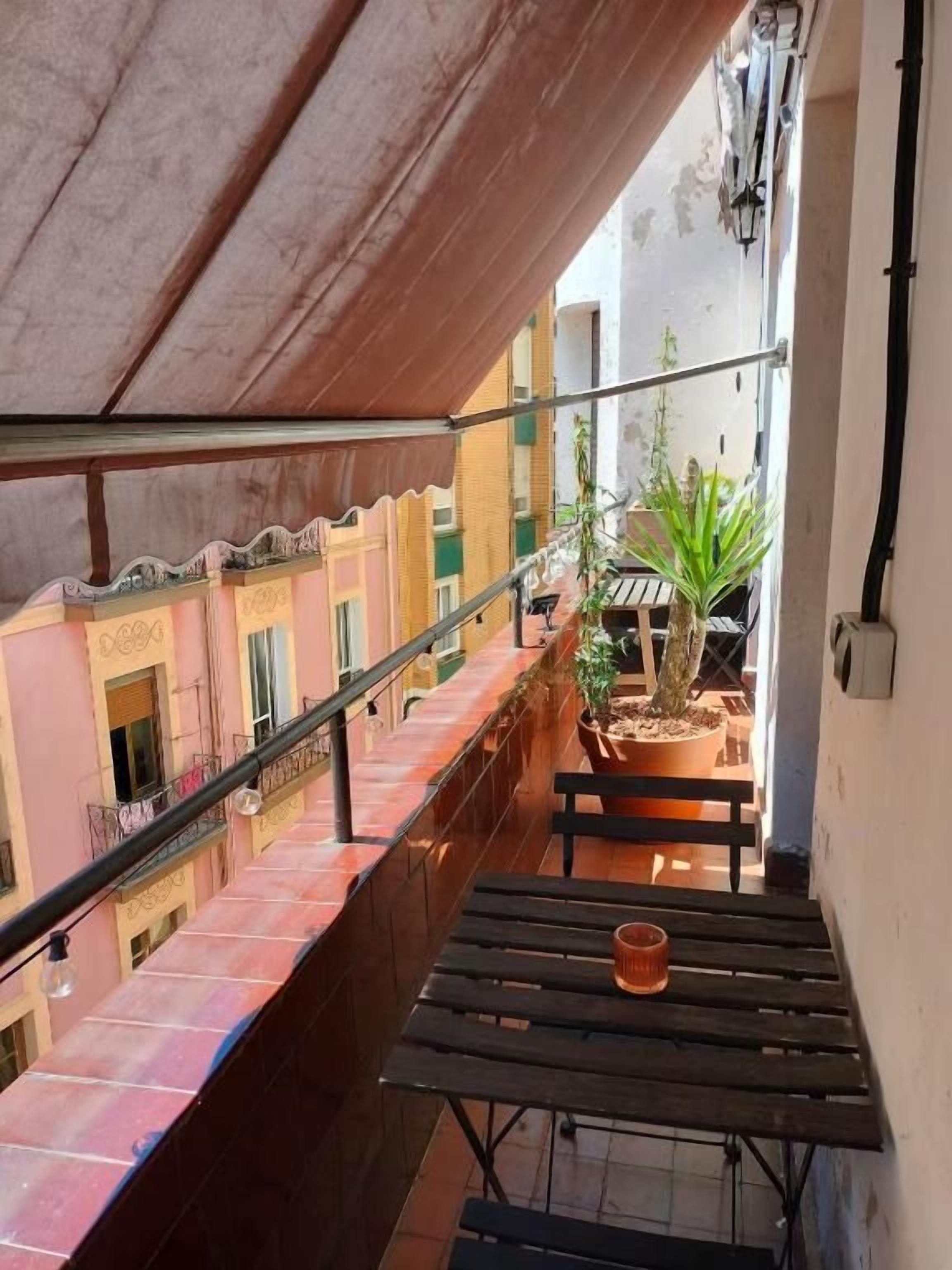 A balcony with a wooden table, potted plants, and a railing.