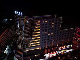 Un hotel de varios pisos con señalización iluminada y una entrada destacada en la esquina.