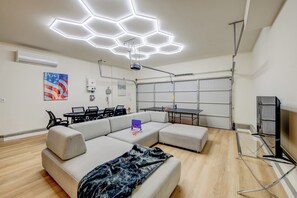 Ein modernes Wohnzimmer mit einem Ecksofa, einem Esstisch und einer Projektoranlage.