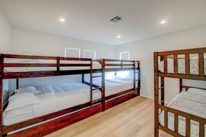 Ein Zimmer mit Etagenbetten, einem Deckenlüfter und einem Fenster mit Leuchte.