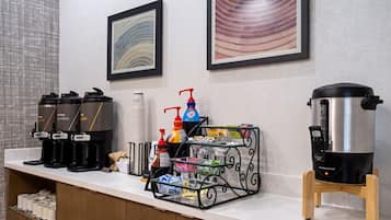 Un buffet de petit-déjeuner d’hôtel avec des machines à café, un distributeur d’eau et une cafetière.