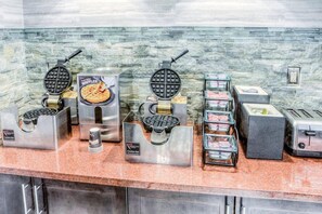 A breakfast bar with waffle makers, a waffle display, a coffee dispenser, and a toaster. - Free Hot Breakfast Buffet |1 Mile from Ohio State University | Heated Indoor Pool (Columbus)