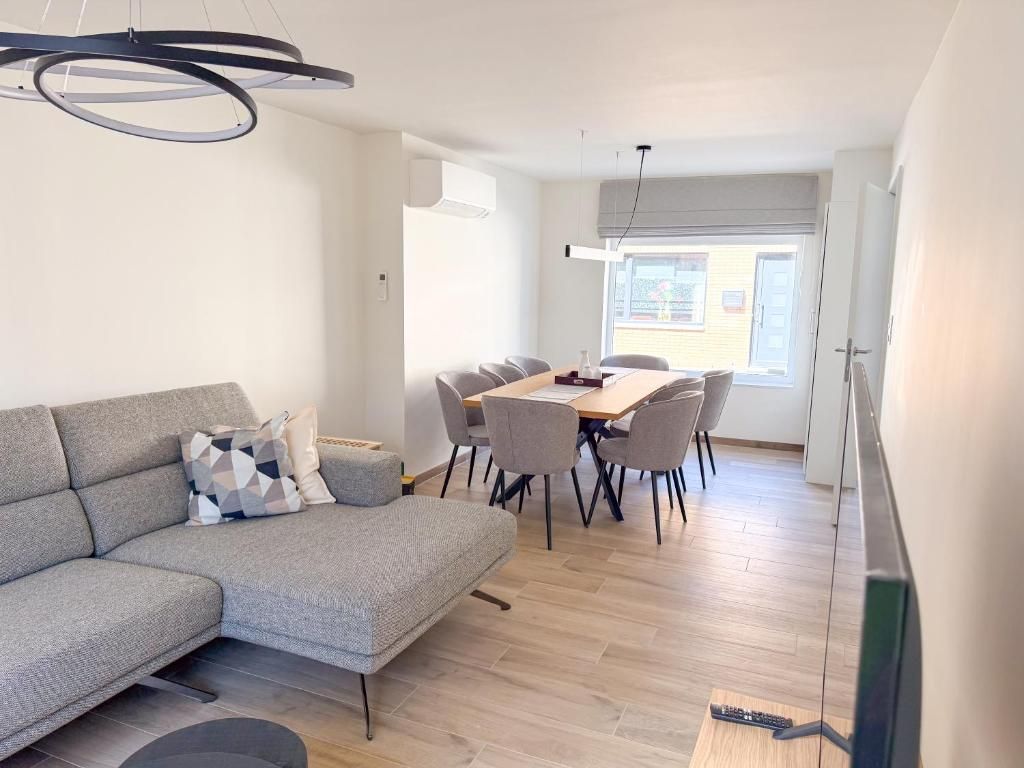 A modern living room with a sofa, dining table, and chairs.
