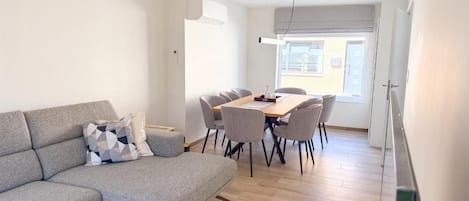 A modern living room with a sofa, dining table, and chairs.