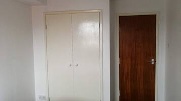 A bedroom with a bed, a wardrobe, and a door.