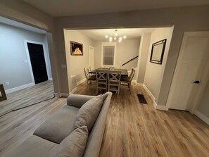 Un comedor con una mesa y sillas de madera, un banco, una araña y una escalera.