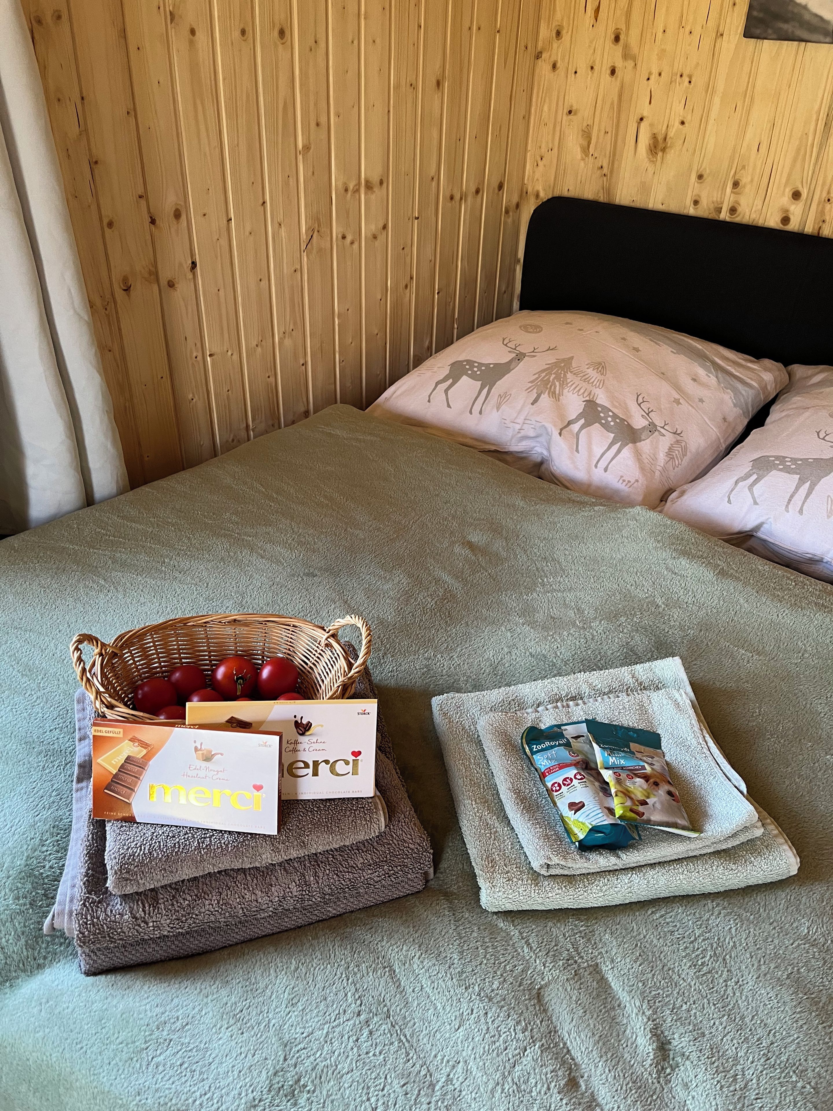 Uma cama com cabeceira de madeira, uma cesta de maçãs, uma caixa de café e uma embalagem de chá.