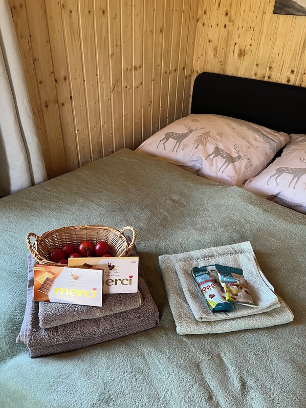 Un letto con testiera in legno, un cesto di mele, una scatola di caffè e una confezione di tè.