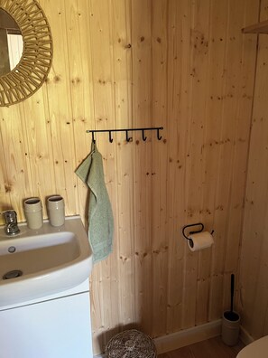 Un bagno con parete in legno, un lavandino, uno specchio e un portasciugamani.