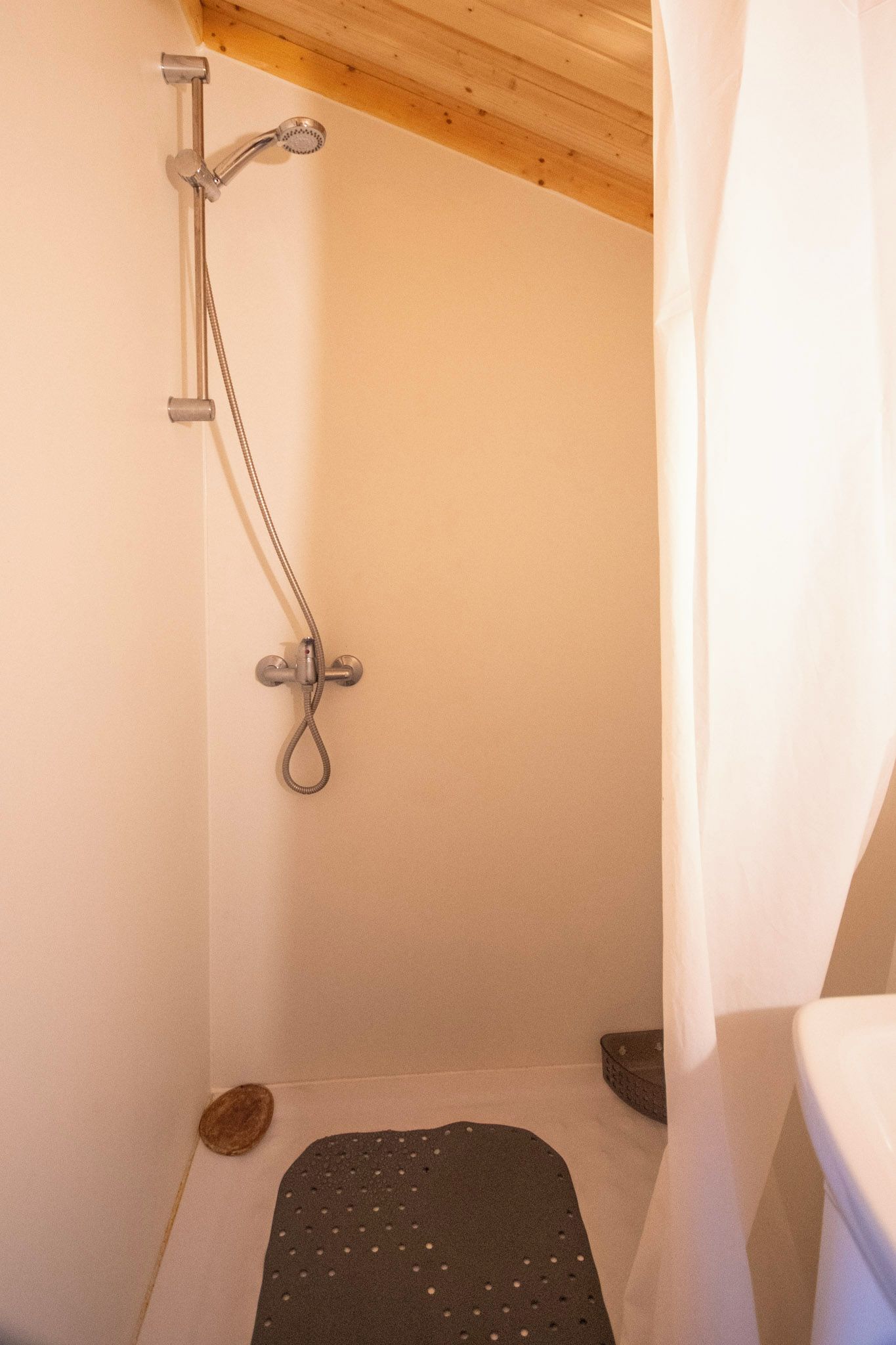 Eine Dusche mit Handbrause und am Wand montiertem Wasserhahn.