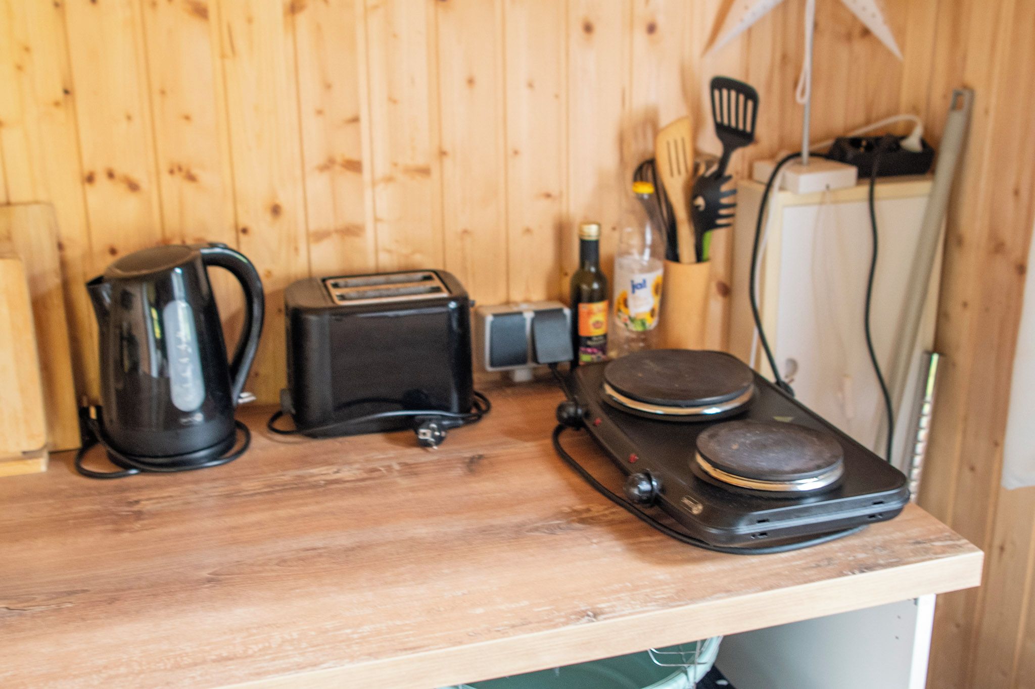 A kitchen counter with a coffee maker, toaster, and a portable stove.