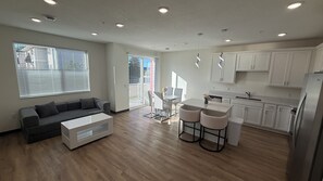 A modern kitchen with white cabinets, a dining area with a table and chairs, and a living room with a sofa and coffee table. - #202-2-bedroom furnished modern Townhome - 2.5 mile from Mayo Clinic (Rochester)