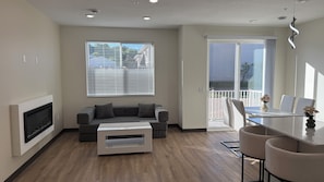 A modern living room with a grey sofa, a white coffee table, and a fireplace. - #202-2-bedroom furnished modern Townhome - 2.5 mile from Mayo Clinic (Rochester)