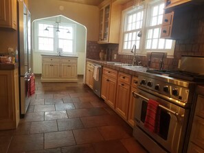 A kitchen with wooden cabinets, a stainless steel stove, and a large window. - The Gnome Home in McKennan Park (Sioux Falls)