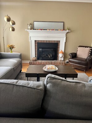 Una sala de estar con chimenea, sofá, mesa de centro y lámpara.