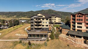 A multi-story hotel with balconies, a pool area, and a view of the surrounding hills. - AMB203 | Dog Friendly | New Luxury Complex | Hot Tub | Winter Shuttle (Steamboat Springs)