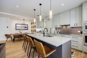 You'll love gathering in this sleek, open kitchen with its spacious island, modern pendant lighting, and warm caramel leather seating—perfect for morning coffee or evening meals together. - AMB203 | Dog Friendly | New Luxury Complex | Hot Tub | Winter Shuttle (Steamboat Springs)