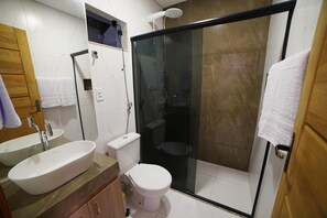 Un baño moderno con un lavamanos grande, inodoro y cabina de ducha con paredes de vidrio.