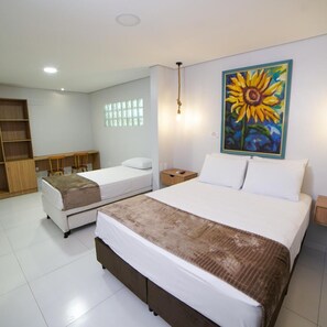 Una habitación de hotel con dos camas individuales, un armario de madera, una mesita pequeña y un cuadro de un girasol.