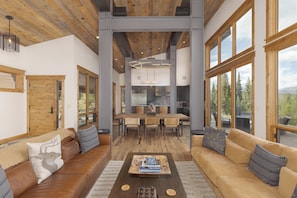 Un espacio habitable amplio con techo de madera, ventanas grandes y una mesa de comedor central.