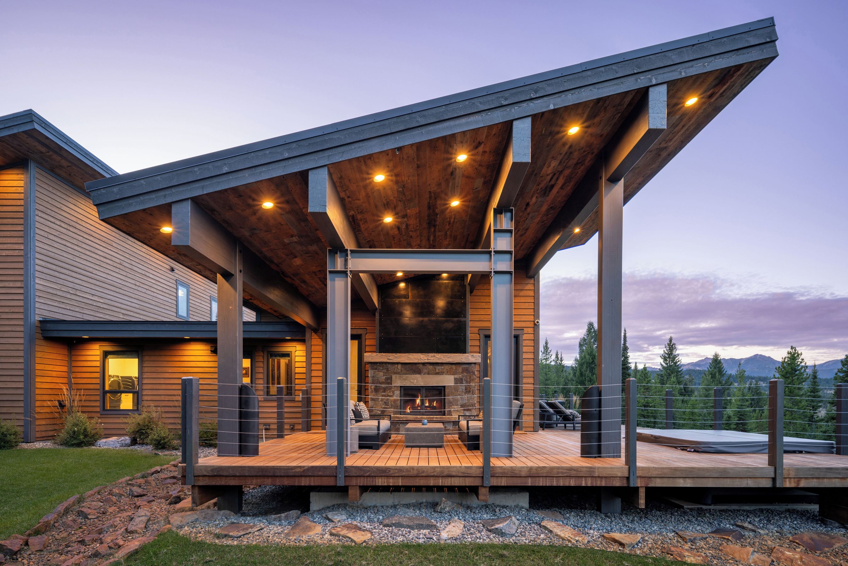 A modern house with a covered outdoor area featuring a fireplace and seating.