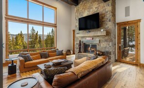 A spacious living room with a stone fireplace, large windows, and a cozy seating area. - Private Luxury Mountain Retreat 3 bdrm w hot tub—near Big Sky & Yellowstone (Big Sky)