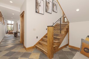Uma escadaria de madeira com grades de metal, que dá acesso a um segundo andar.