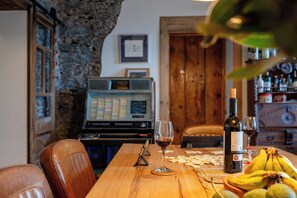 Una mesa de madera con una botella de vino, una copa y un racimo de plátanos.