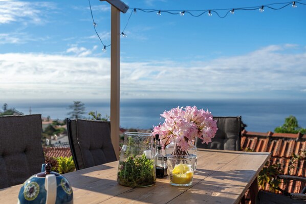 A wooden table with a glass containing flowers, a glass with a yellow substance, and a blue and white mug.