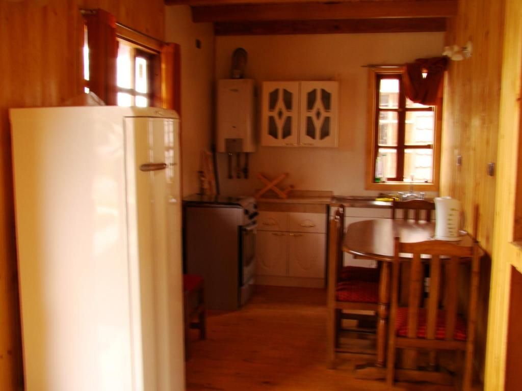 Une cuisine compacte équipée d’un réfrigérateur, d’une cuisinière et d’un coin repas avec une table et des chaises.