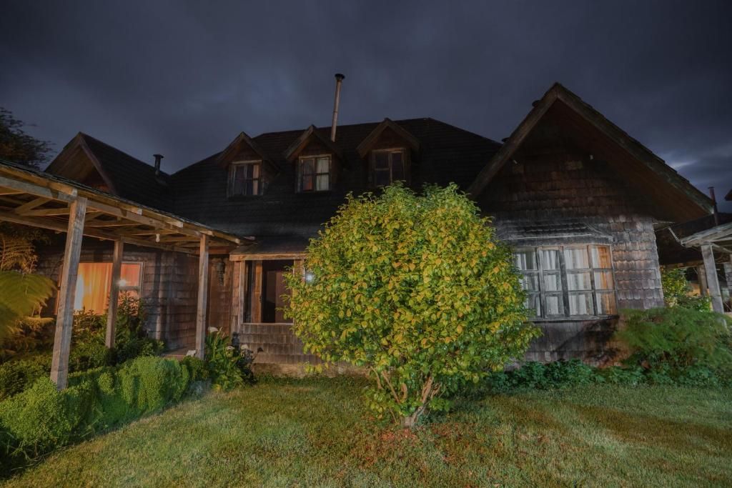 A two-story wooden house with a covered porch and a well-maintained garden.