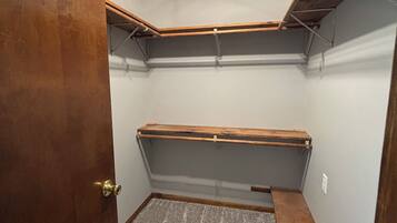 Una habitación de esquina con puerta de madera, una lámpara en el techo y estanterías empotradas.