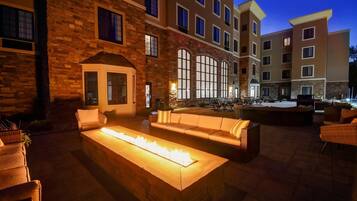 A courtyard with outdoor seating, a fire feature, and a building with multiple windows and balconies.