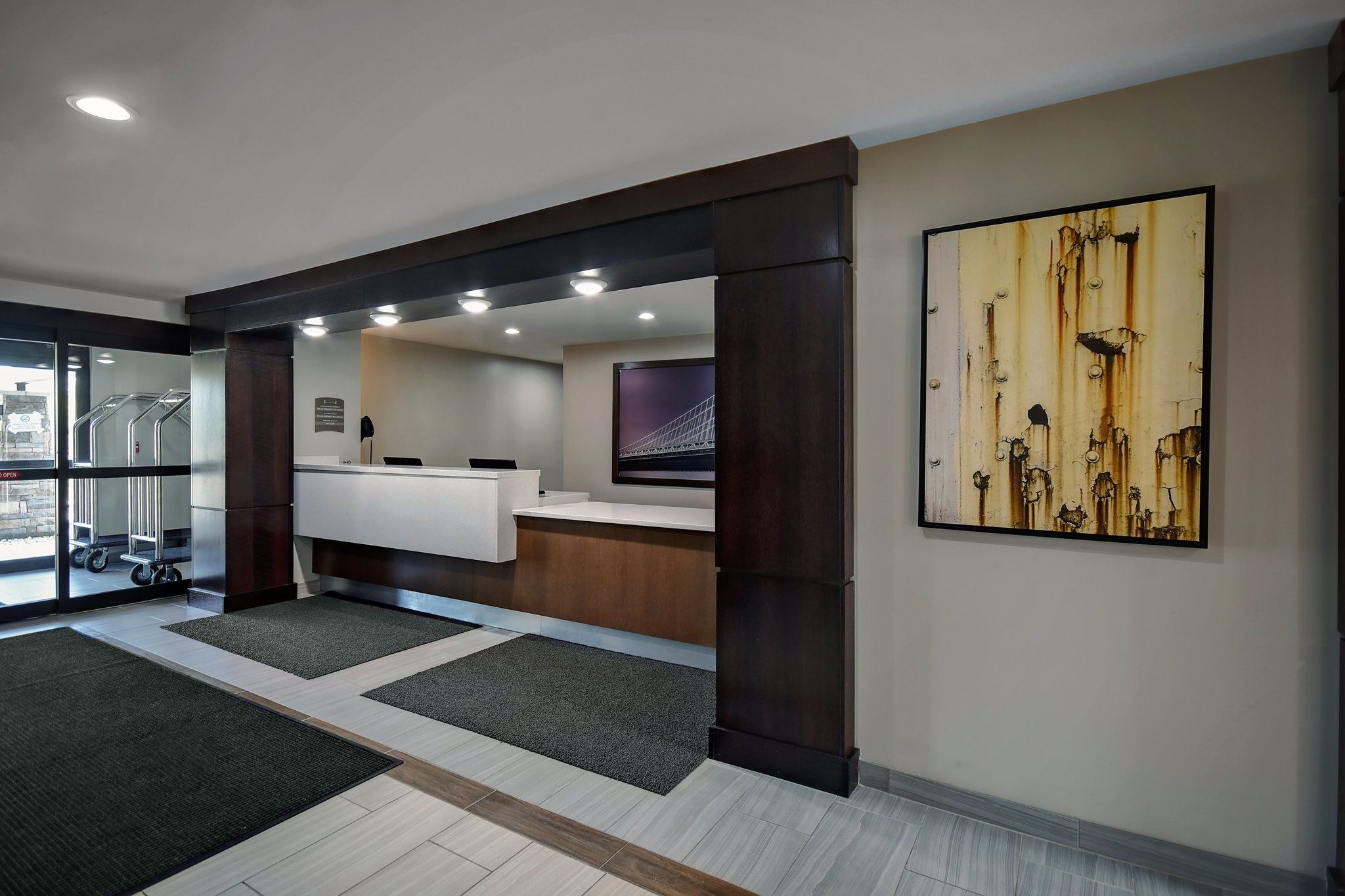 A reception area with a counter, a large abstract painting, and a view of the outside through glass doors.