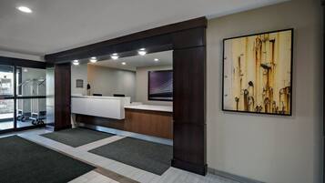 A reception area with a counter, a large abstract painting, and a view of the outside through glass doors.