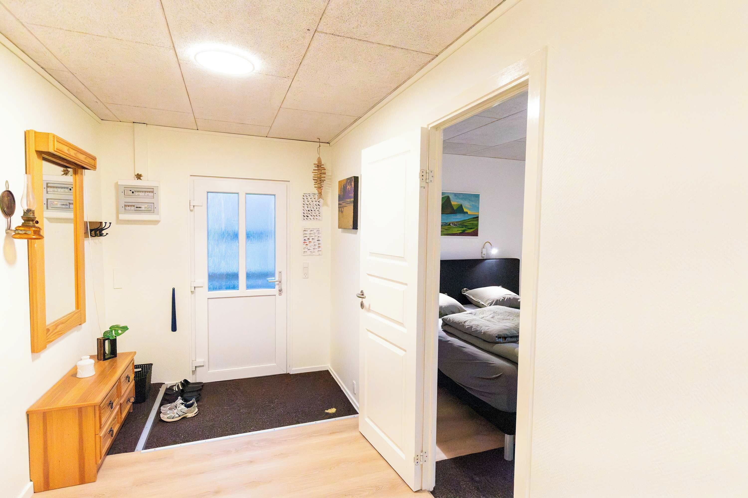 Ein Hotelzimmer mit einem Bett, einem Schreibtisch, einem Spiegel und einer Tür zu einem anderen Raum.