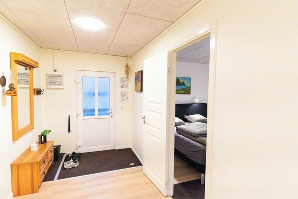 Ein Hotelzimmer mit einem Bett, einem Schreibtisch, einem Spiegel und einer Tür zu einem anderen Raum.