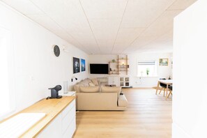 Ein modernes Wohnzimmer mit einer Couch, einem Flachbildfernseher und einem Essbereich mit Tisch und Stühlen.