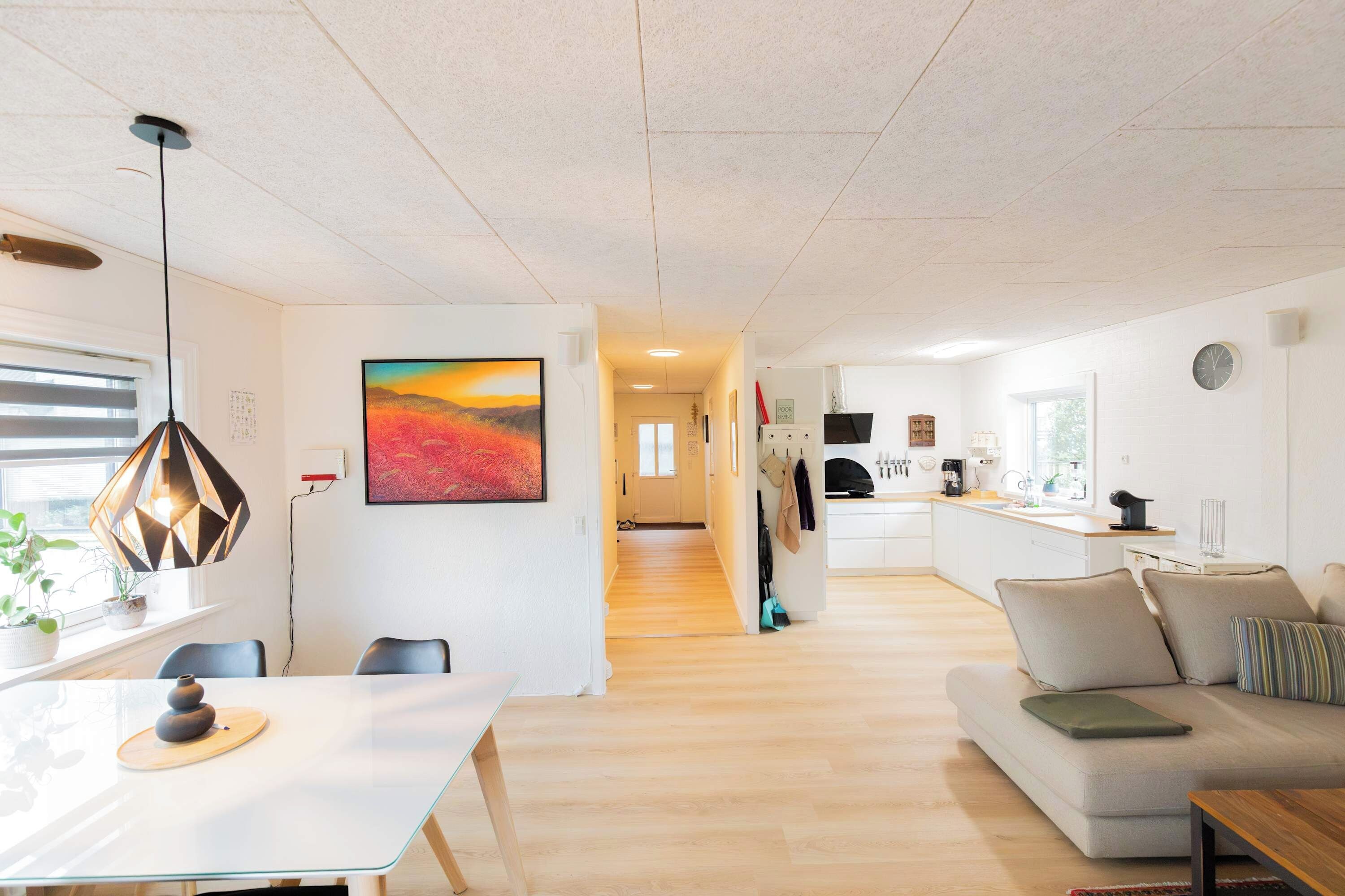 Een moderne woonruimte met een eethoek, een bank, een keuken en een gang die naar een andere kamer leidt.
