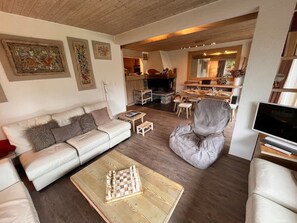 A cozy living room with a sofa, a gaming table, and a grey bean bag chair. - Sunny apartment, close to the slopes and shops (Les Allues)