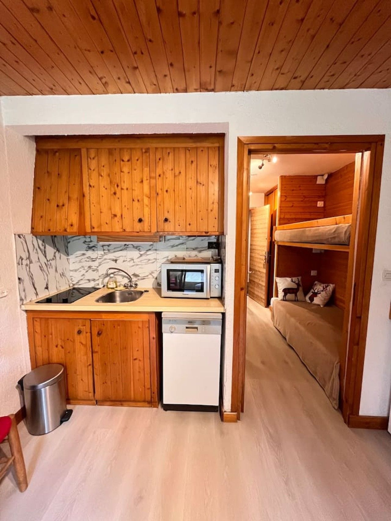 A compact kitchen with wooden cabinets, a microwave, and a dishwasher.