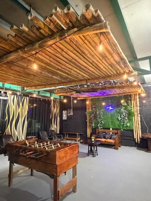 A room with a foosball table, bamboo ceiling, and a green wall with plants.