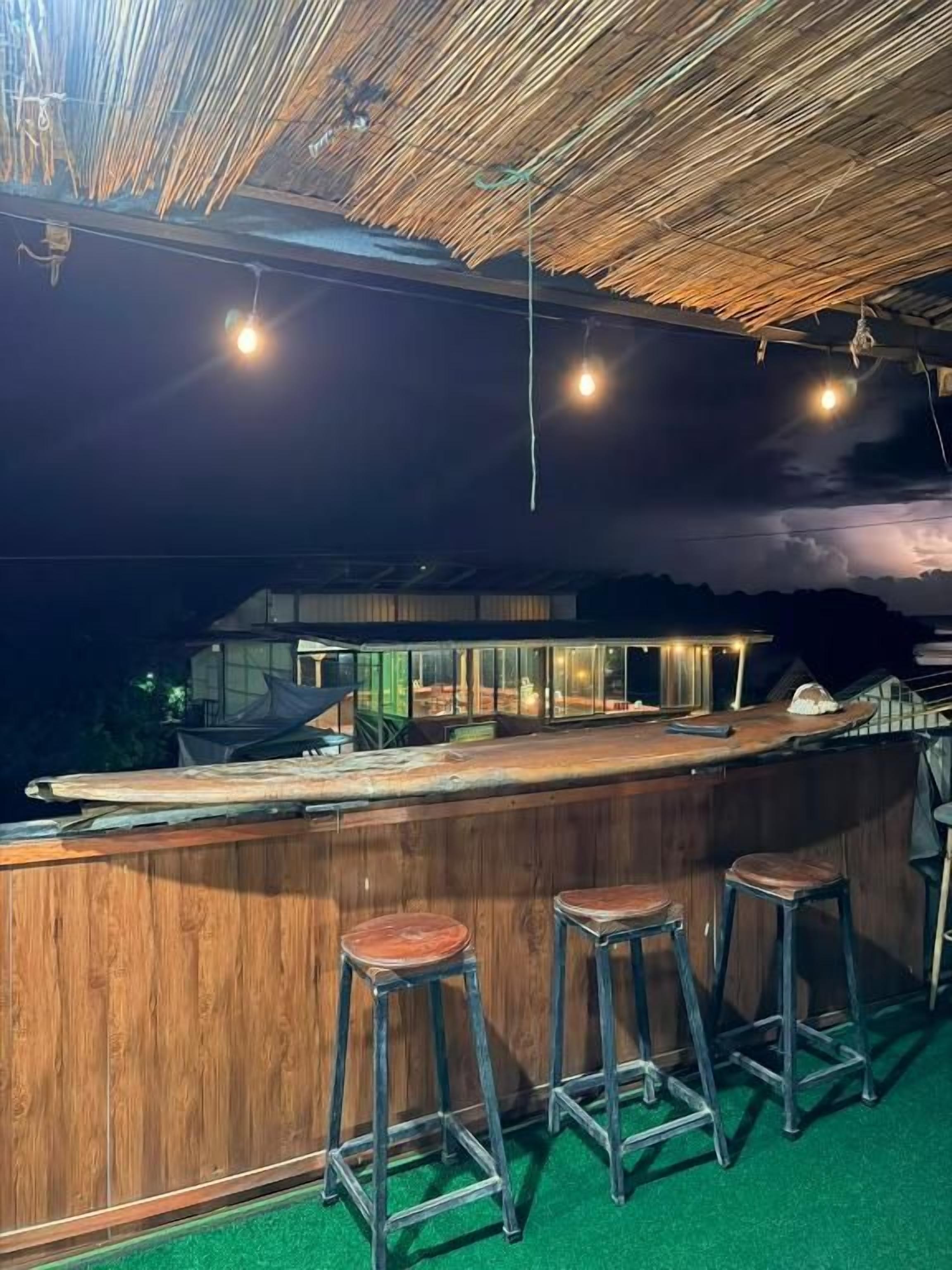 A bar area with stools, a counter, and a view of the sea.